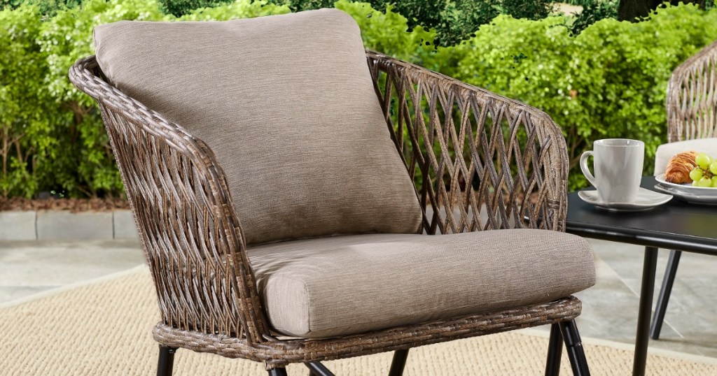 wicker rocking chair with removable cushions on patio with tress in background