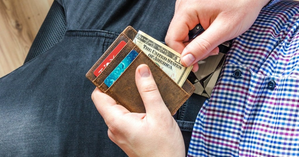 Man adding cash to wallet in lap