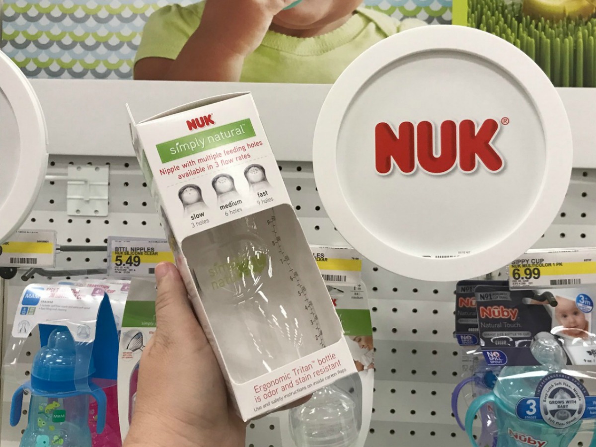 Hand holding Nuk Simply Natural bottle in store aisle
