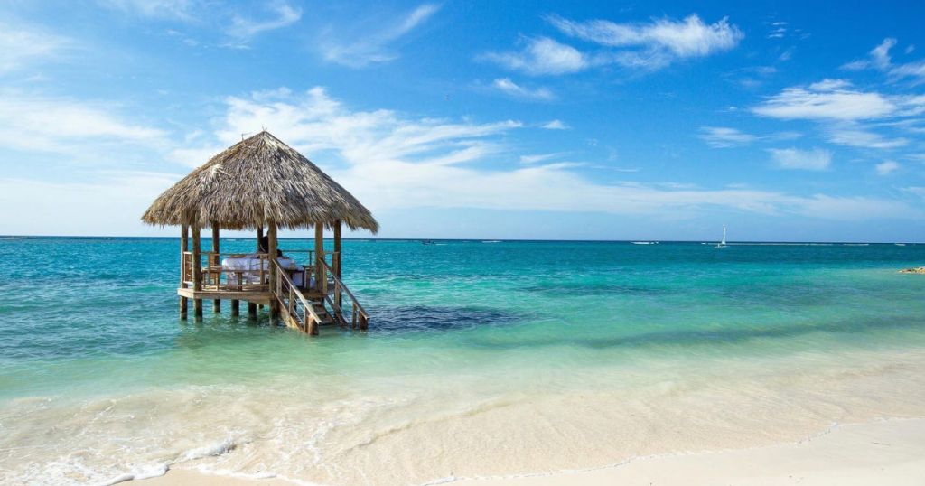 tiki hut in the ocean with sand on the beach Sandals Beach Resorts