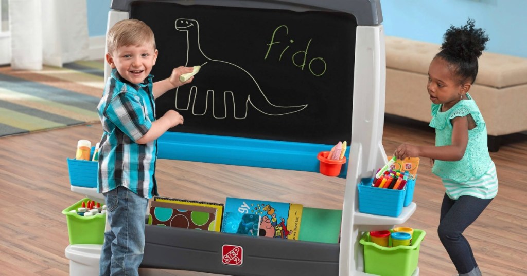 boy and girl drawing on jumbo chalk board