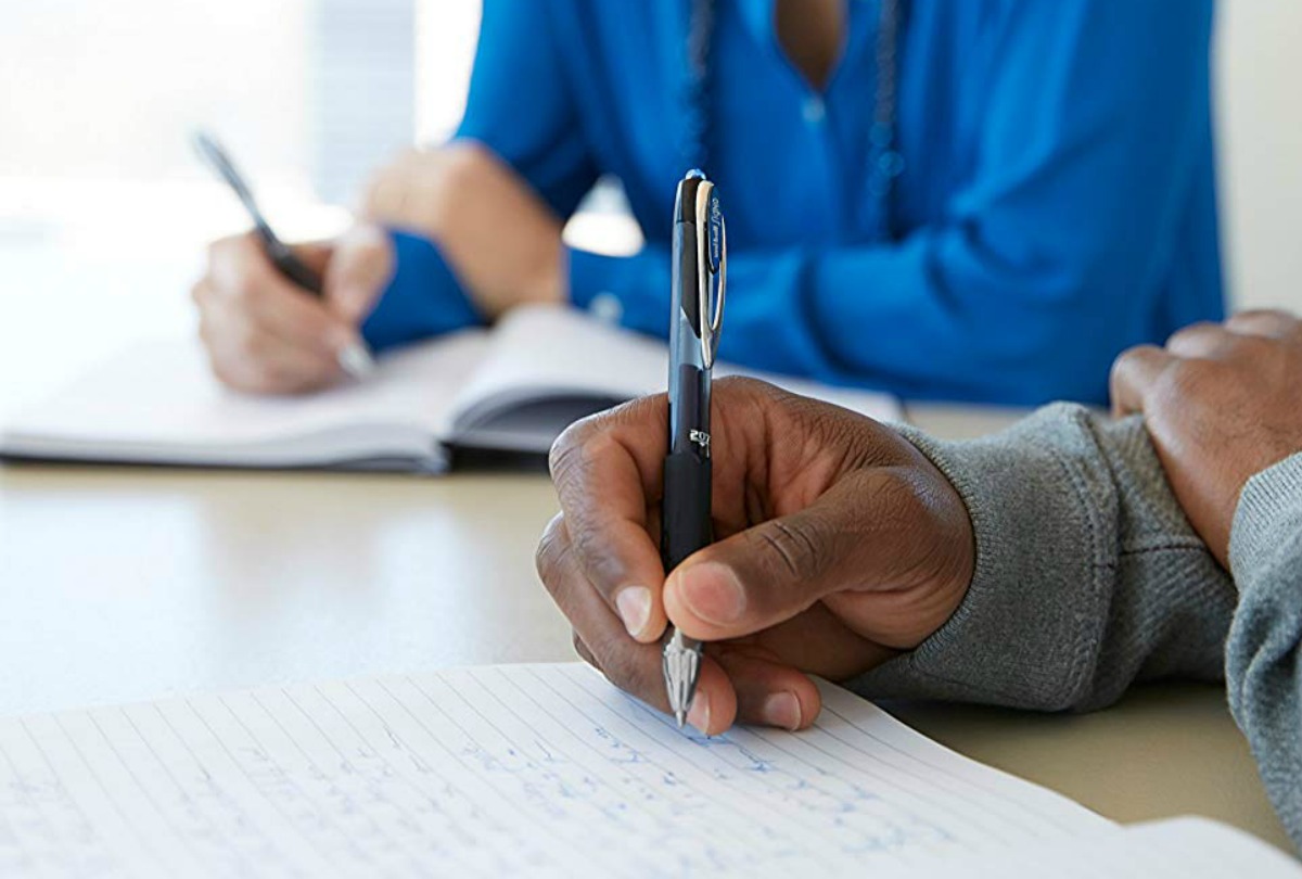 Man writing with a uni-ball brand gel pen in conference room