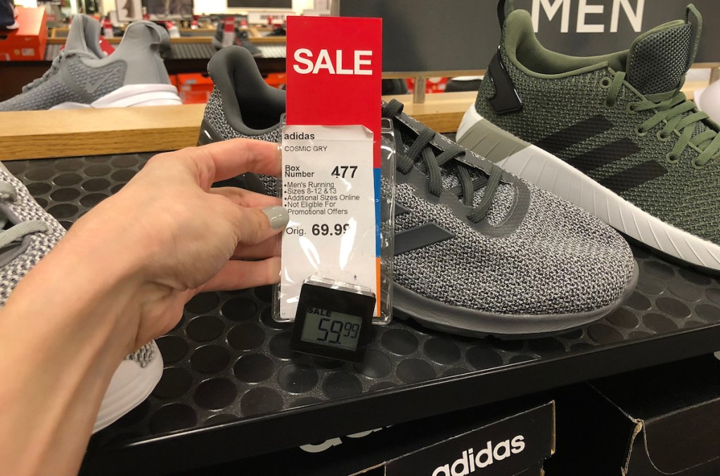 hand holding red sale tag on adidas shoes