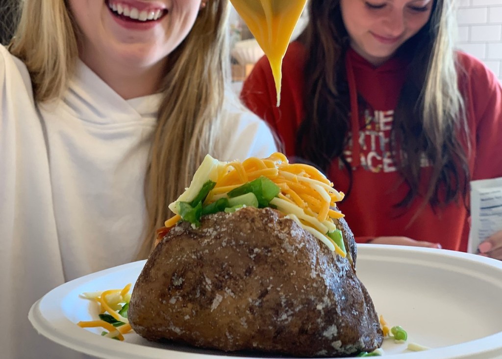 loaded baked potato on plate with girls smiling
