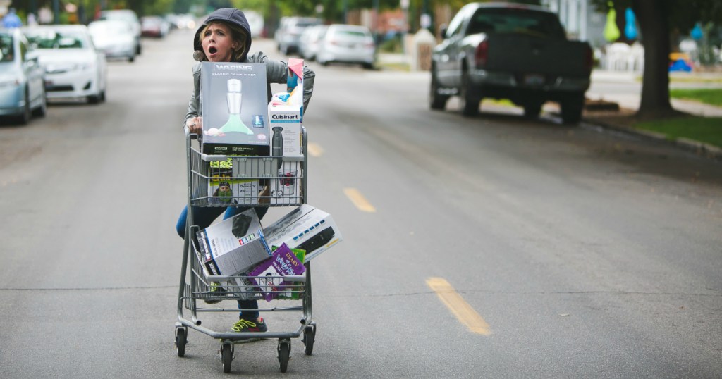 woman pushing shopping cart down street