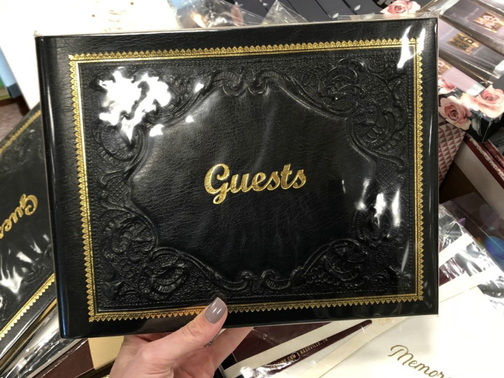 hand holding black book that says guests