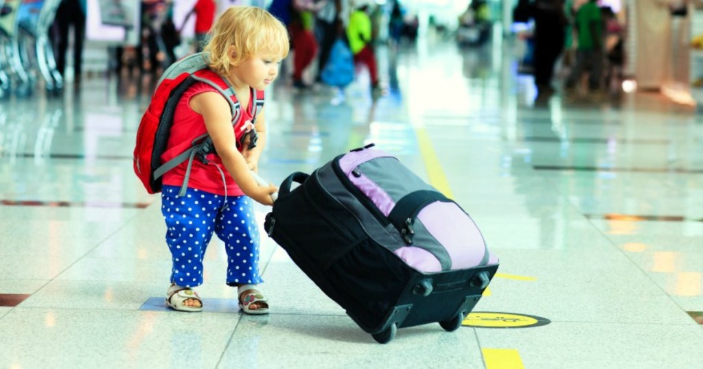 child holding luggage at airport
