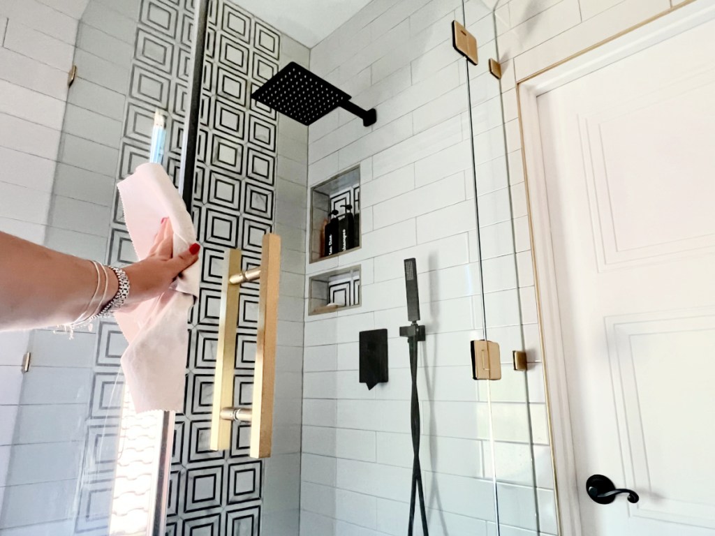  woman doing her own house cleaning services by cleaning shower doors with car microfiber cloths