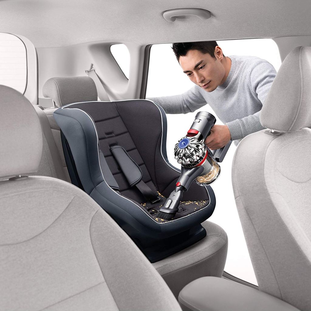 man vacuuming car seat with Dyson V7 handheld vacuum