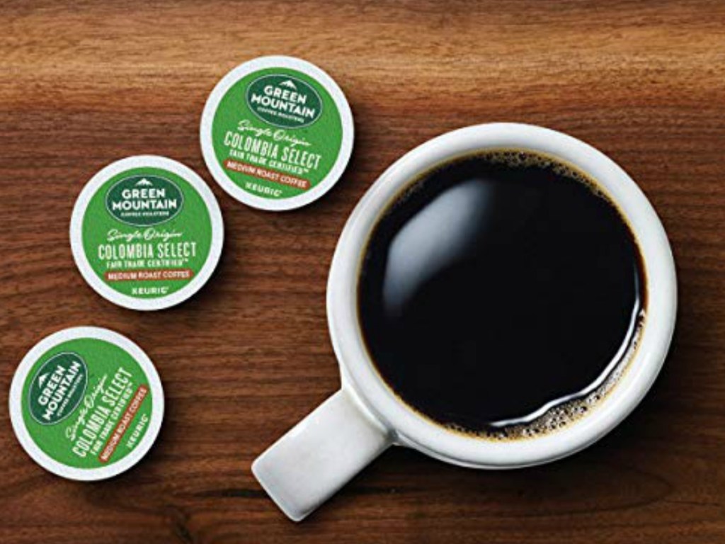 cup of coffee with three coffee pods next to it