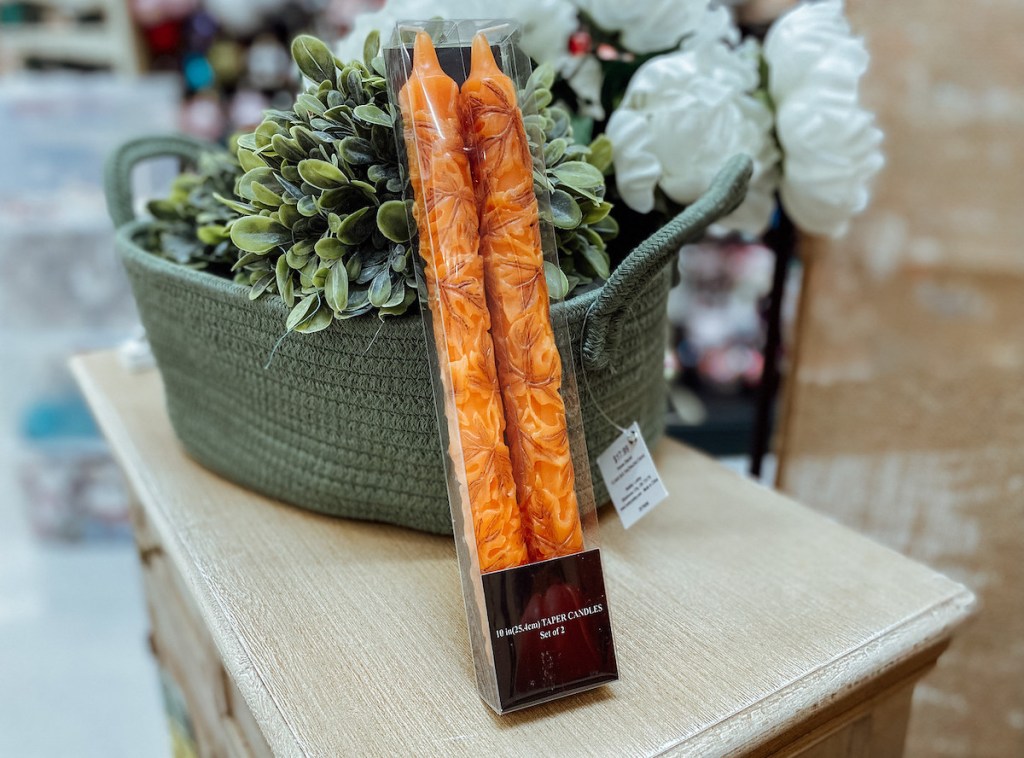 orange leaves taper candles leaning on plant in store