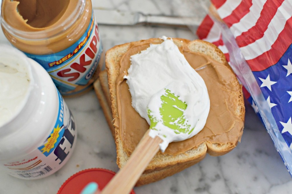 spreading marshmallow fluff on a peanut butter sandwich