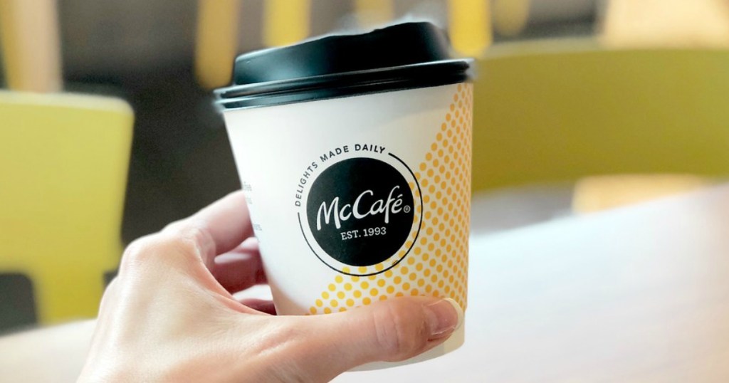 hand holding up mccafe coffee cup with blurred background of the restaurant