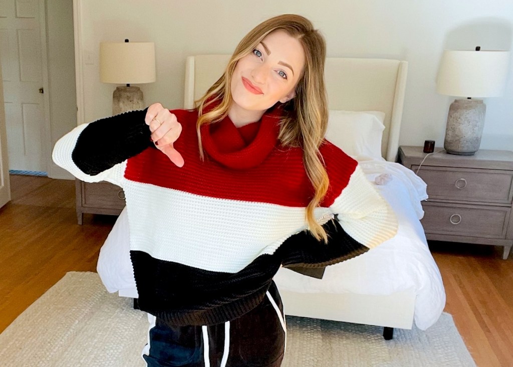 woman holding a thumbs down wearing color block sweater