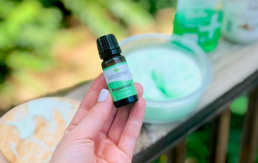 hand holding a small amber bottle of peppermint essential oil