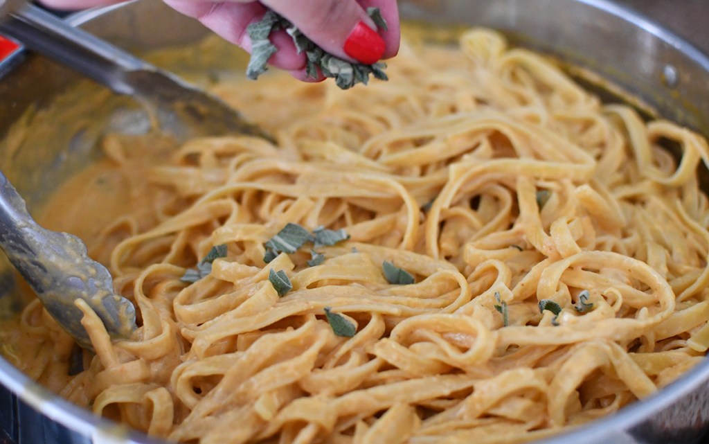 sprinkling in sage on top of pumpkin fettuccine alfredo