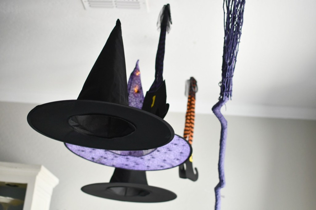 witch hat hanging with lights and a broom