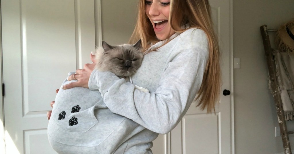woman wearing light gray sweatshirt hoodie with cat inside