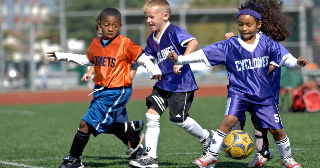 Kids wearing soccer uniforms on field