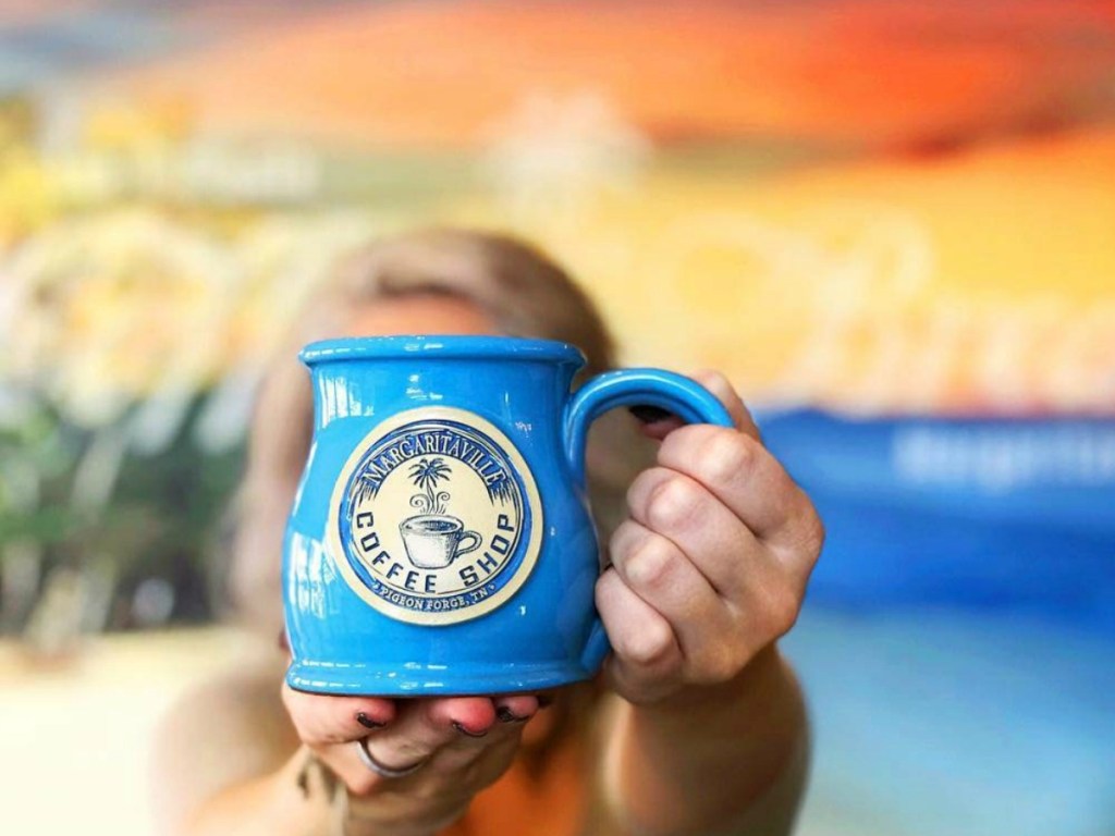 person holding coffee mug by sunset