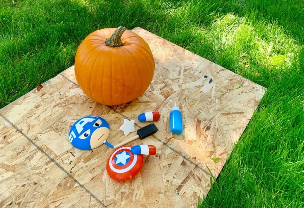 Captain America no-carve pumpkin pieces and pumpkin outside on plywood