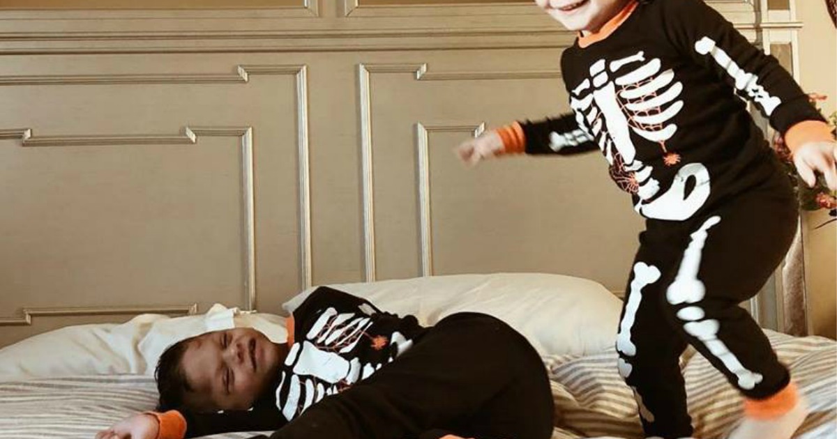kids jumping on bed wearing halloween pjs