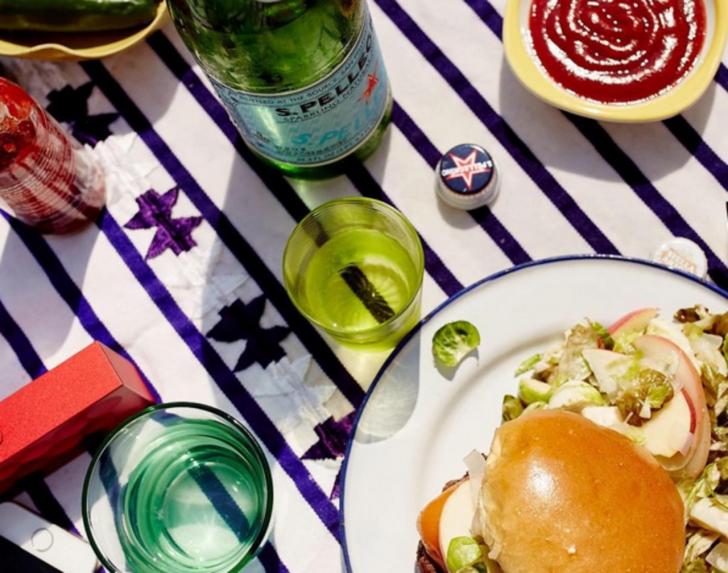 San Pellegrino sparkling water bottle next to a burger and glasses