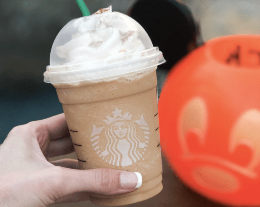 Woman holding Secret Cinderella Drink at Starbucks next to pumpkin