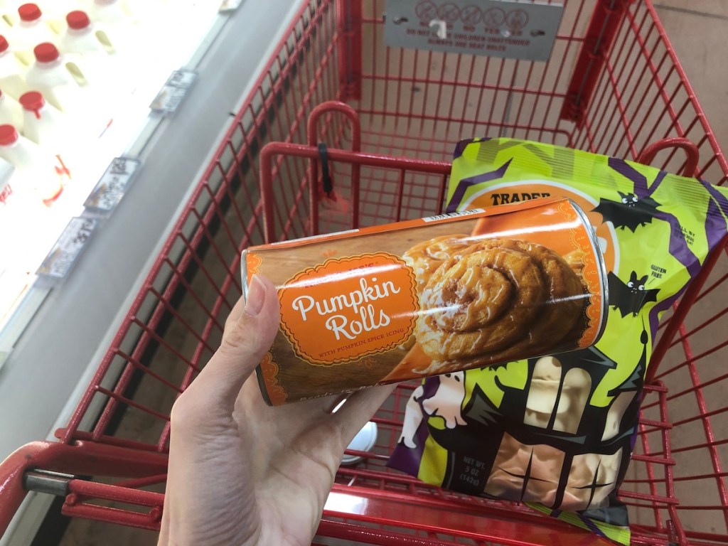 women's hand holding Trader Joe's pumpkin rolls in store by cart