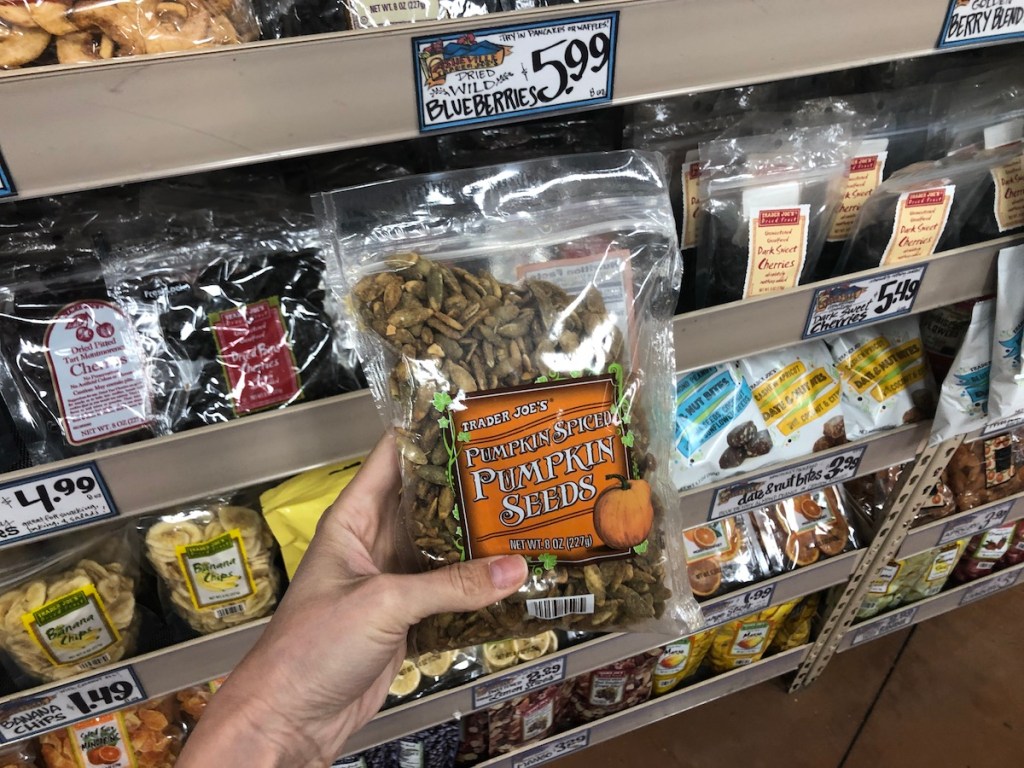 women's hand holding Trader Joe's pumpkin spiced pumpkin seeds in store