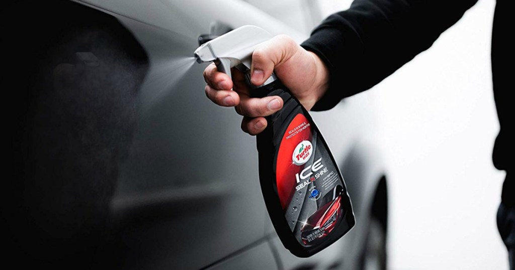 man spraying black car with turtle wax product