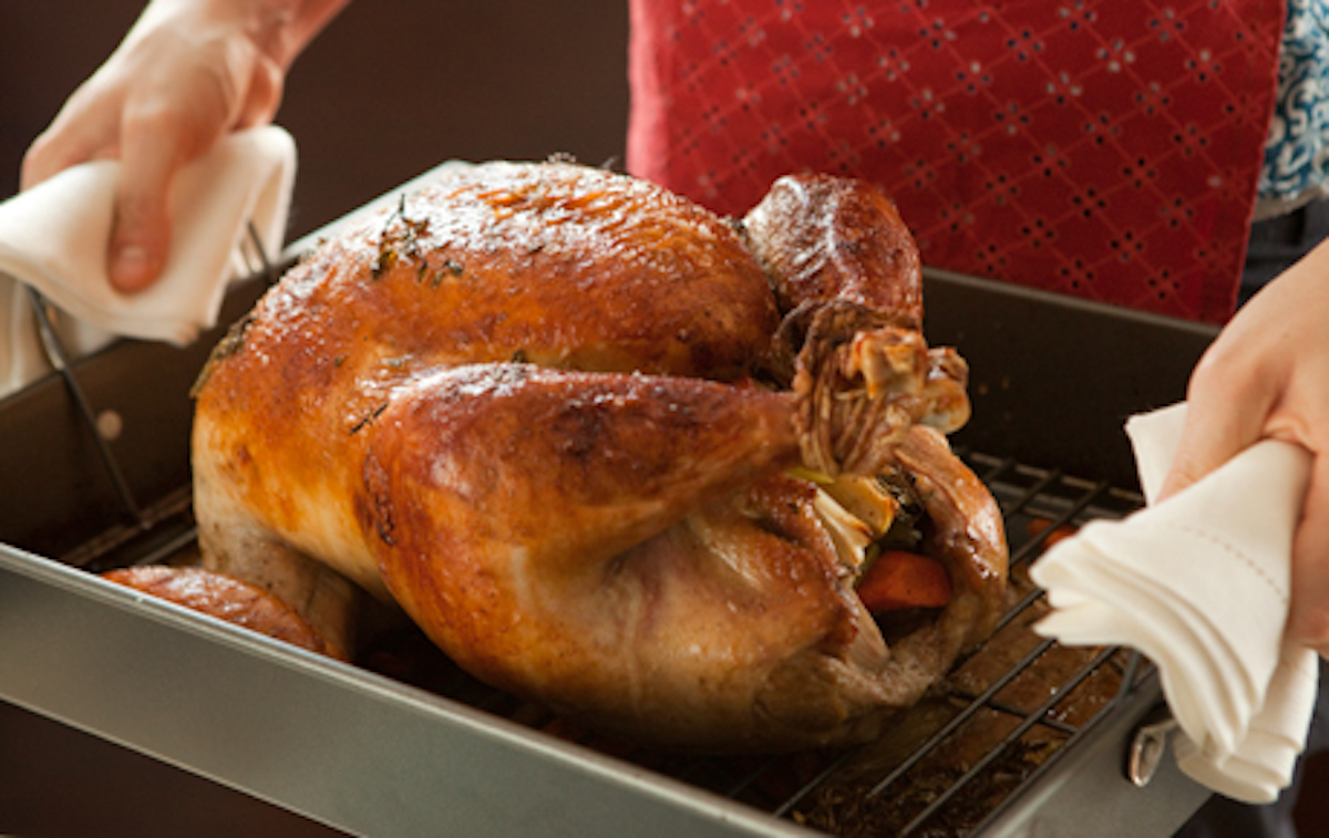 person holding pan with roasted turkey