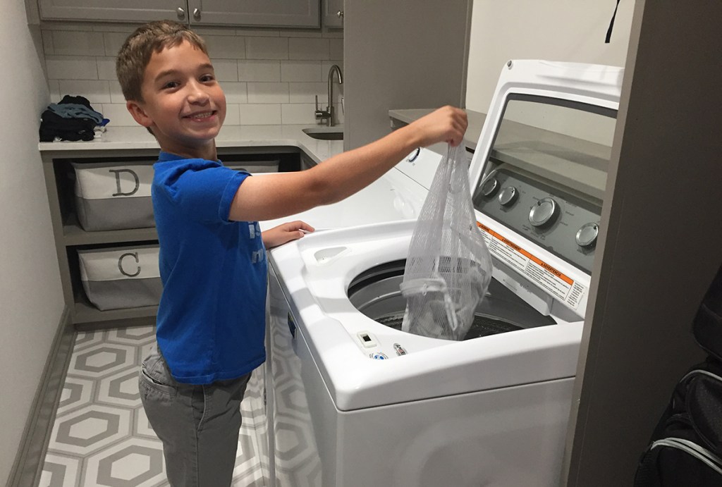 young boy putting mesh bag in washing machine