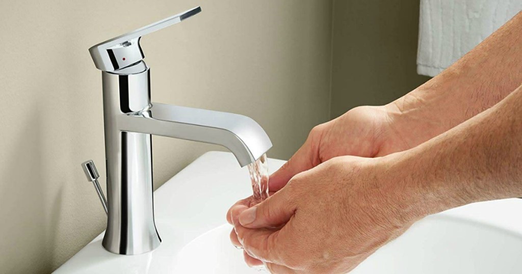 pair of hands washing under water in bathroom sink