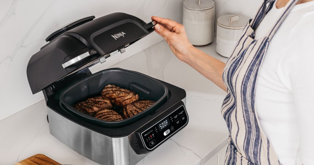 woman using ninja foodi indoor grill in kitchen 