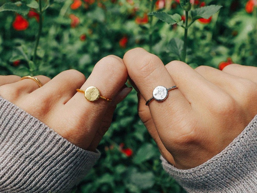 close up of hands wearing puravida compass ring in silver and gold