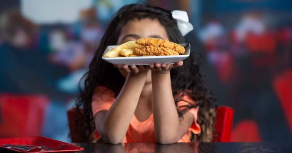 girl holding plate of red robin chicken tender kids meal