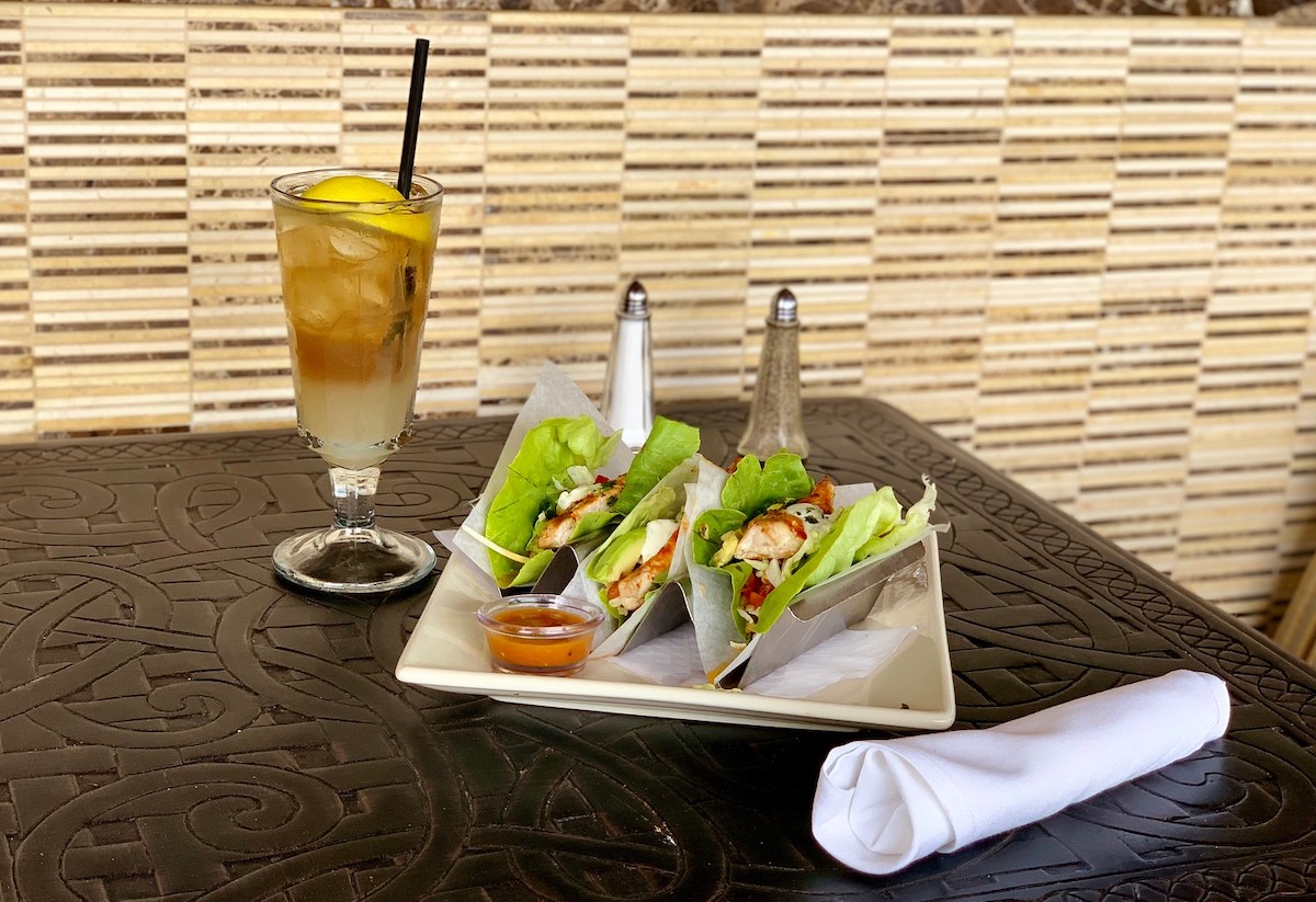 three salad tacos on plate with glass of iced tea