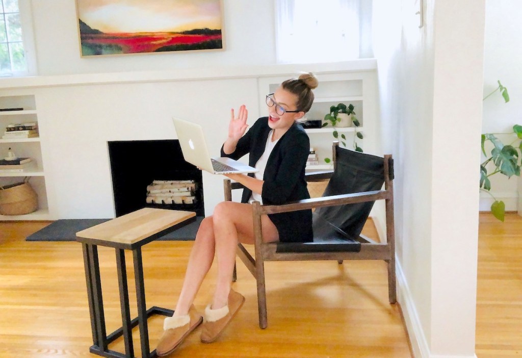 woman waving to laptop sitting in chair