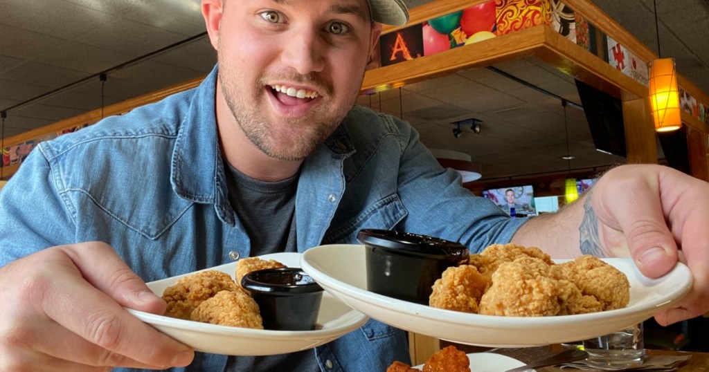 man holding plates of chicken wings at Applebee's