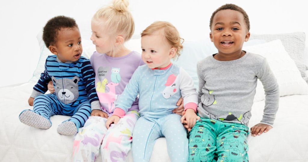 babies and children sitting on bed in carter's pajamas
