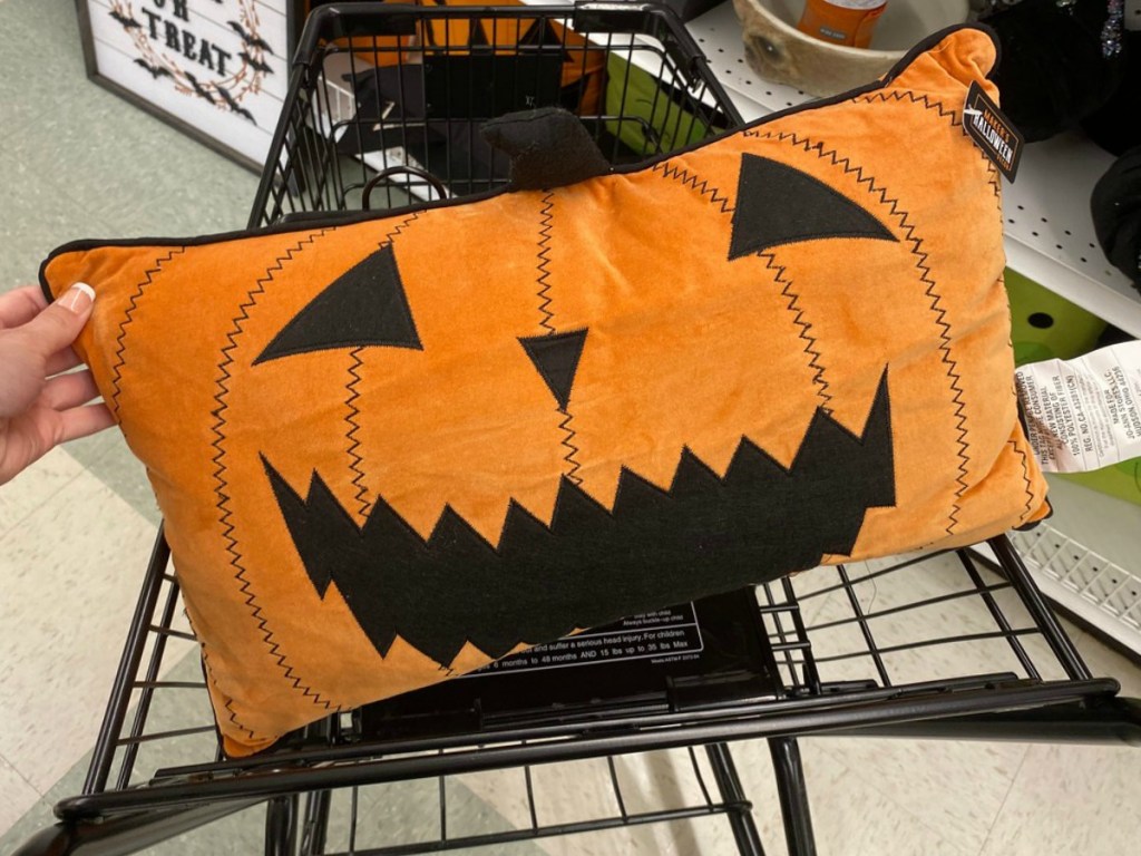 Halloween Jack-O-Lantern themed throw pillow in hand, in shopping cart, in-store