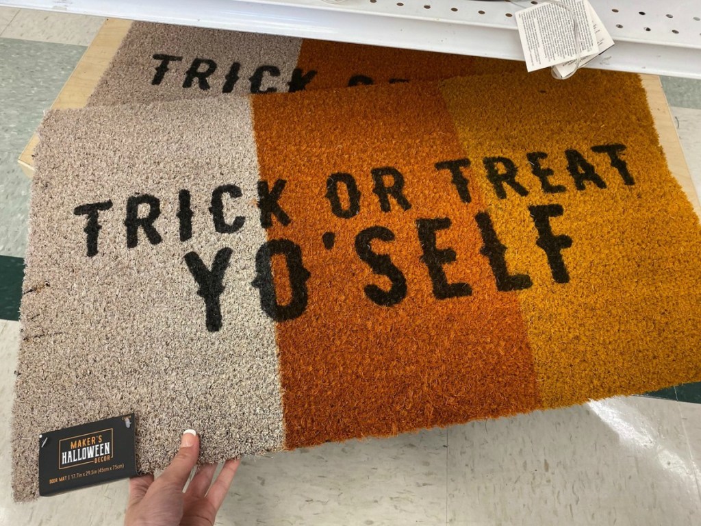 Hand holding Candy Corn themed door mat coir rug