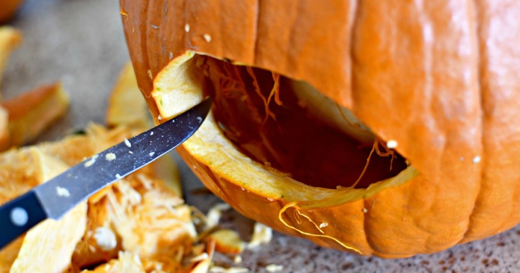 carving an eye into a pumpkin with a knife