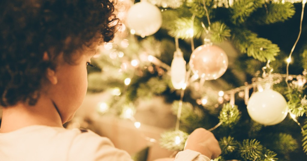 child decorating Christmas tree