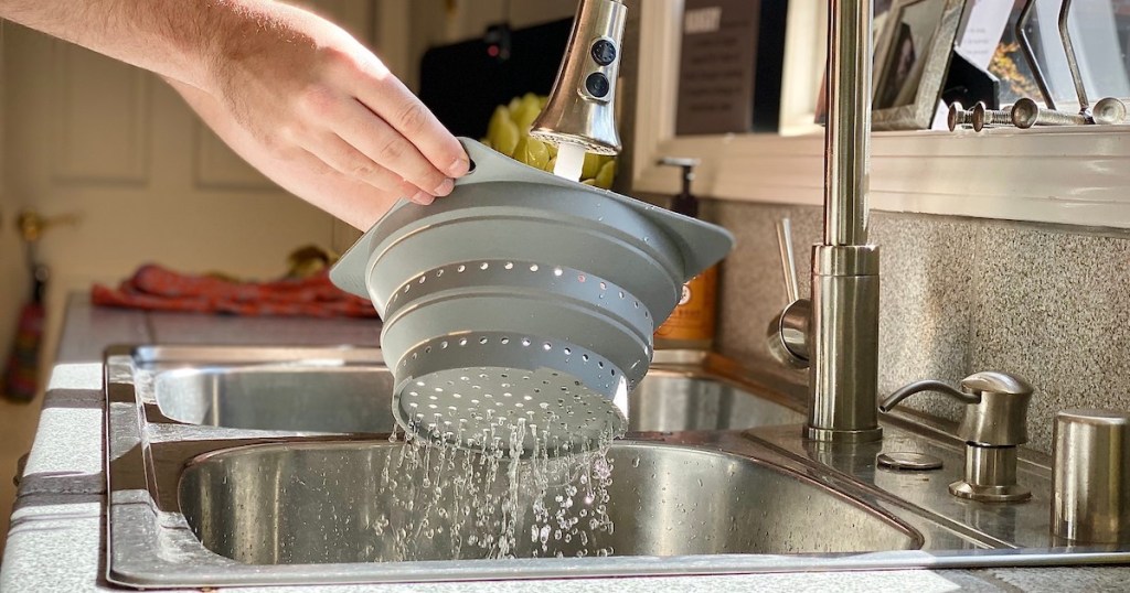 hands holding strainer colander over sink
