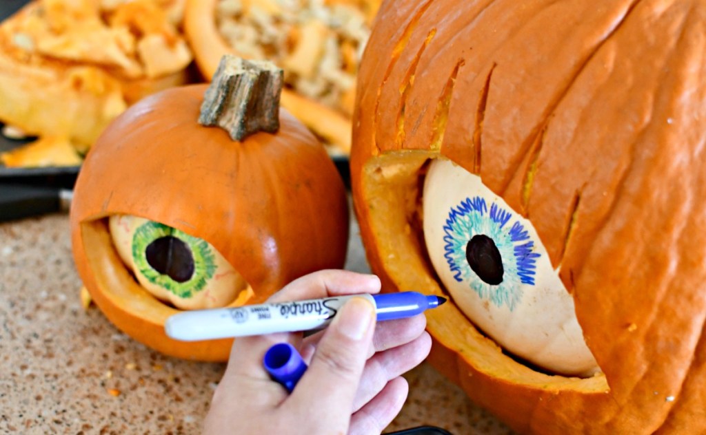 drawing eye details on a white pumpkin