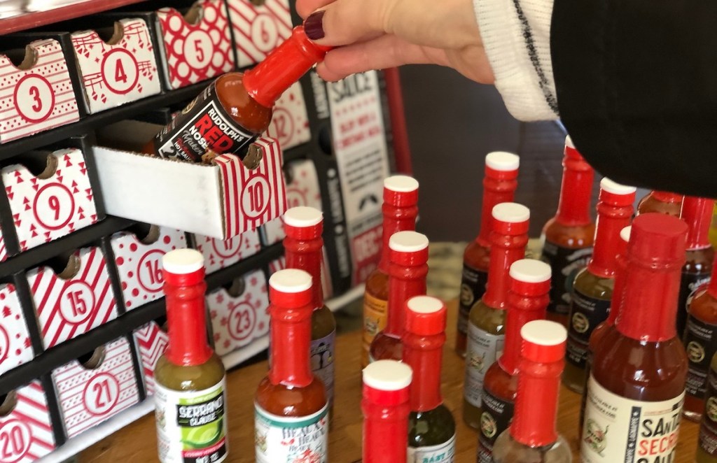 hand taking out box of hot sauces from advent calendar