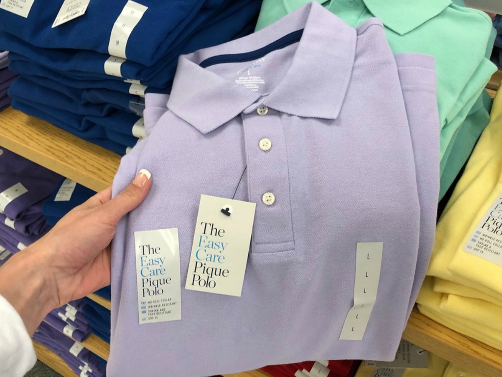 hand holding lavendar colored shirt by store display