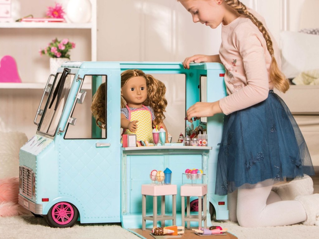 girl playing with ice cream truck and doll
